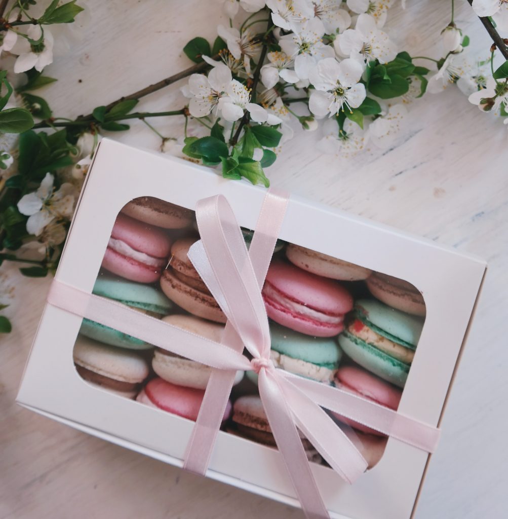 Box of different coloured macaroons with pink ribbon