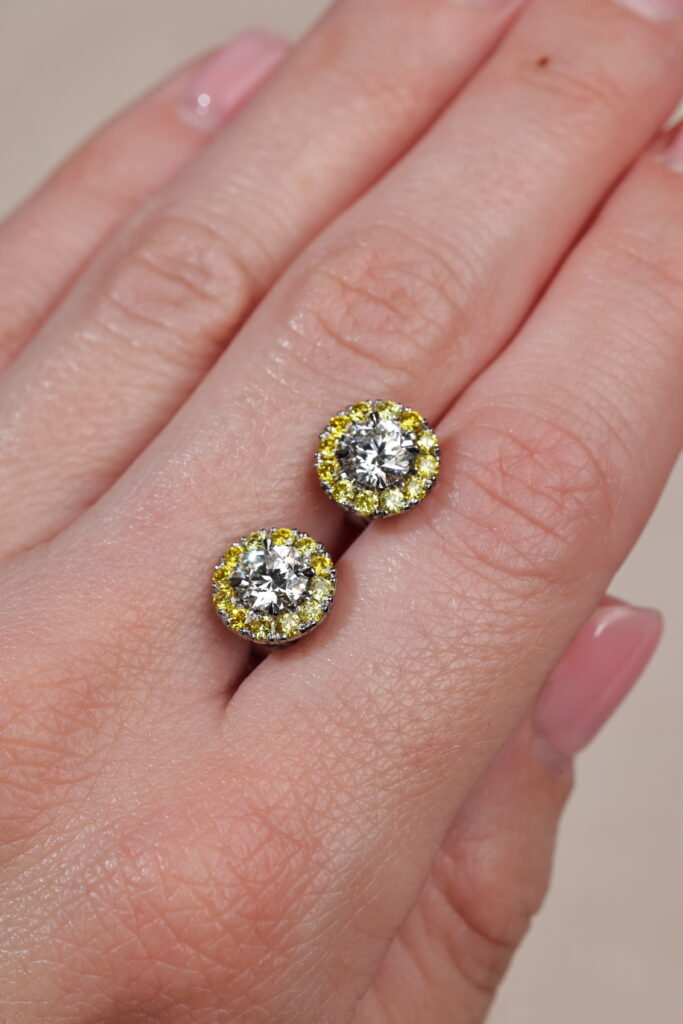 Yellow diamond halo earrings on hand