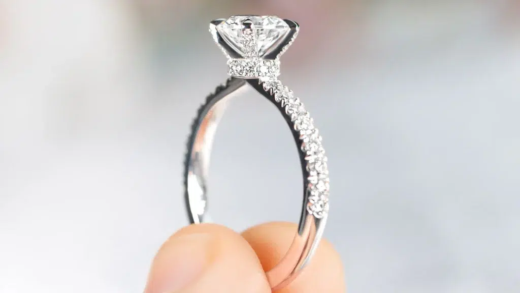 Hidden halo silver engagement ring being held between fingers