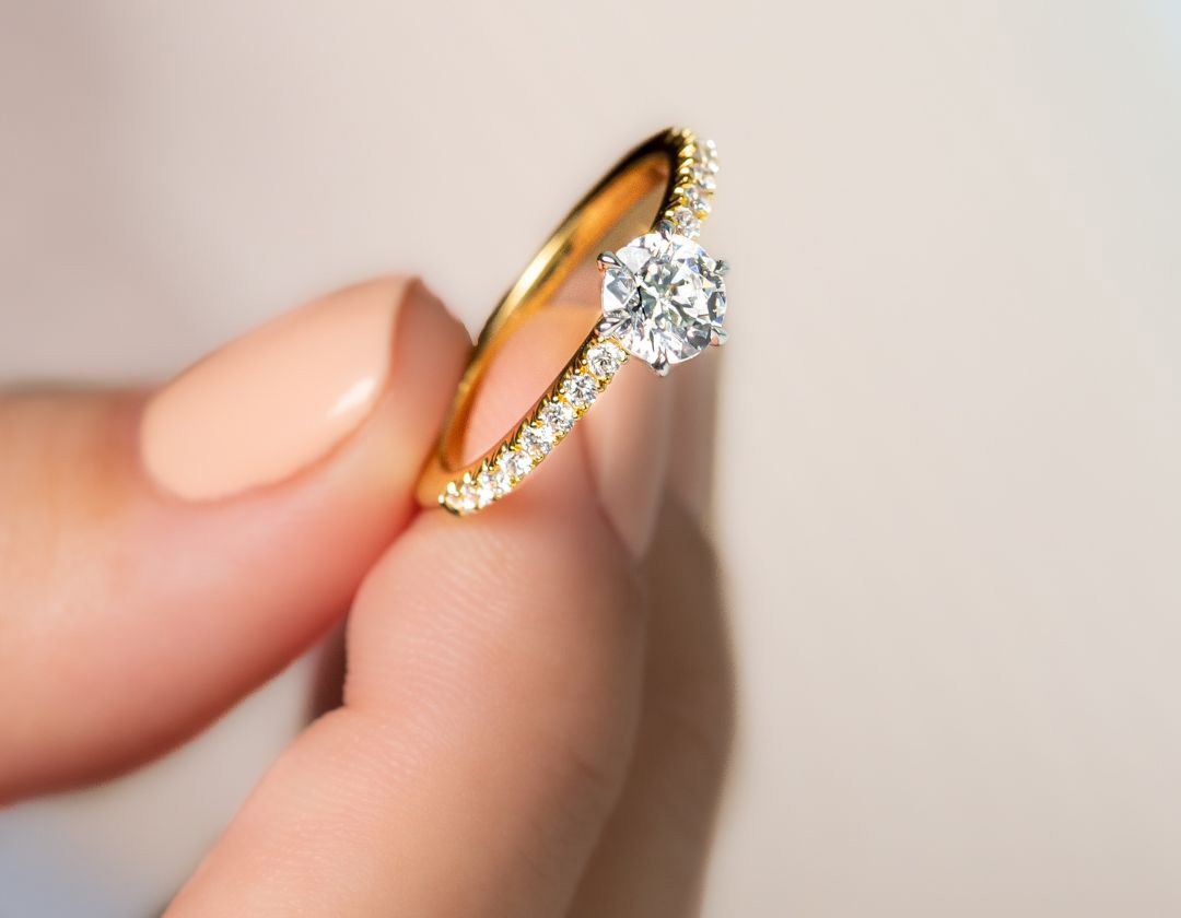 woman holding round brilliant cut between fingers