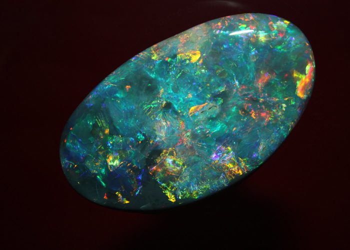 A photo of the Aurora Australis Opal on a black background. Photo Credit: Atlmann and Cherny